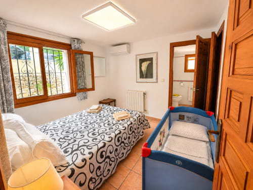 Spacious bedroom in Casa Emilia villa, Moraira with double bed, crib, wooden furnishings and en-suite bathroom