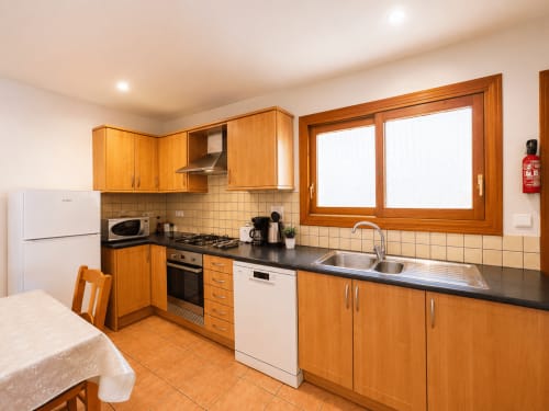 Modern kitchen in Casa Emilia villa, Moraira with wooden cabinets, black countertops, stainless steel appliances and dining