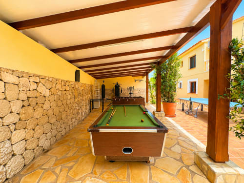 Covered patio with billiards table and stone walls at Casa Emilia villa in Moraira, Spain