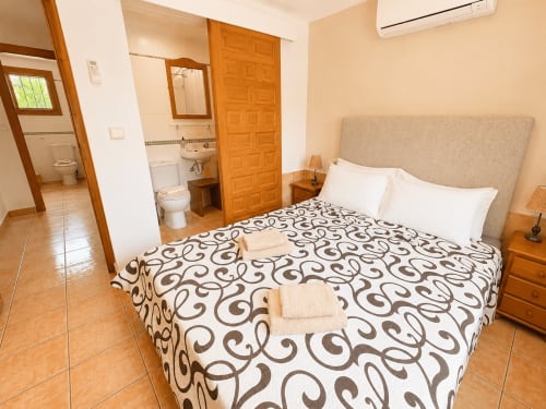 Spacious bedroom at Casa Emilia villa in Moraira with queen bed, en-suite bathroom, wooden furnishings and terracotta