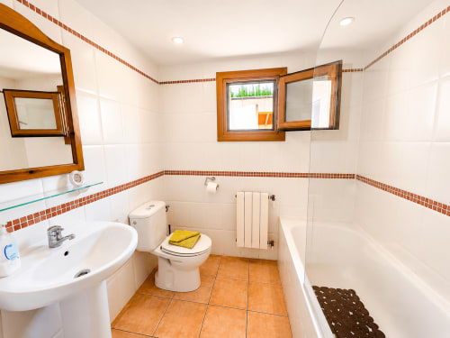 Bright bathroom at Casa Emilia villa in Moraira with terracotta tiles, white fixtures, orange trim, and windows