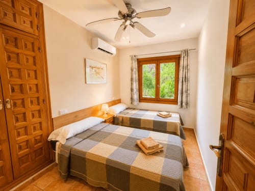 Twin bedroom with wooden furnishings at Casa Emilia villa in Moraira, featuring garden views and ceiling fan