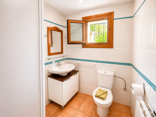 Bright bathroom in Casa Emilia villa, Moraira featuring white tiles, teal trim, wooden mirrors, sink with vanity, and terra