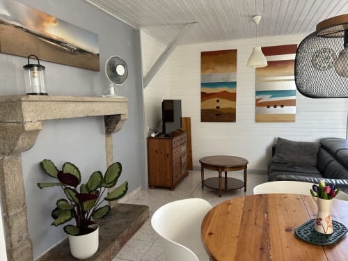 Bright living room in Gîte Les Plages with wooden furniture, fireplace, artwork, and desert-themed decor at Le Pré d'Olonne