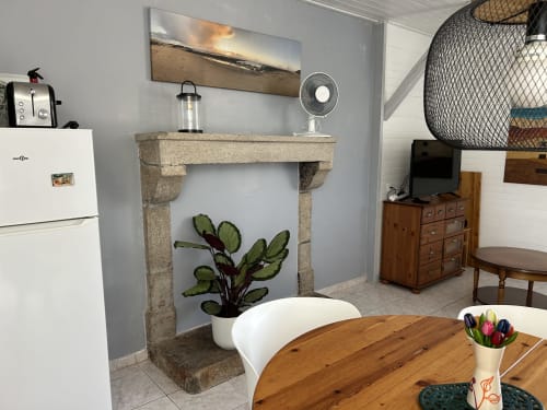 Le Pré d'Olonne gîte living area with stone fireplace, wooden dining table, white appliances and vintage décor