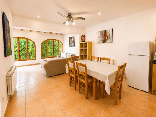 Open-plan dining and living area in Casa Emilia villa, Moraira with wooden table, chairs, and archway windows overlooking