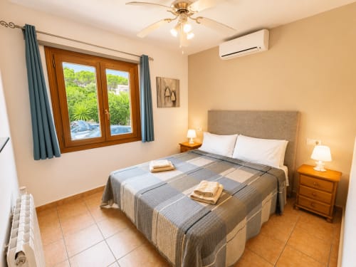 Bright bedroom in Casa Emilia villa, Moraira with pool view, wooden furnishings, and air conditioning