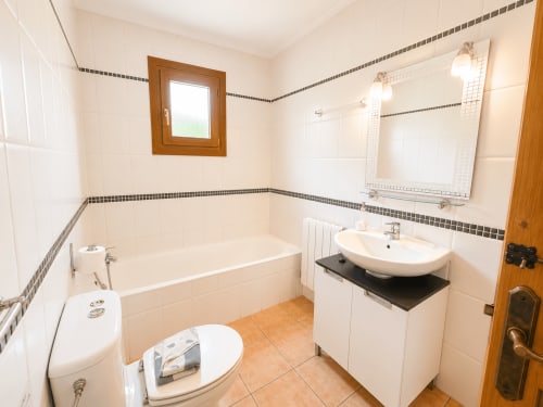Bright bathroom in Casa Emilia villa, Moraira with white tiles, bathtub, sink, mirror and wooden door frame