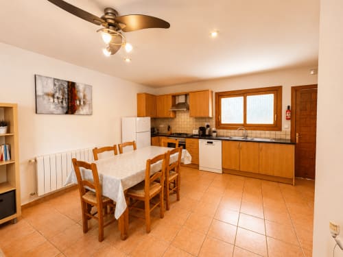 Spacious kitchen-dining area in Casa Emilia villa, Moraira, with wooden cabinets, terracotta tiles, and dining table seating