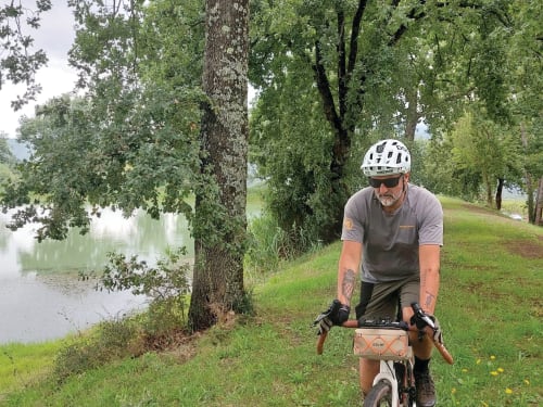Cyclist riding on scenic path by river near Country House Bosco d'Olmi in Sant'Andrea del Garigliano, Italy