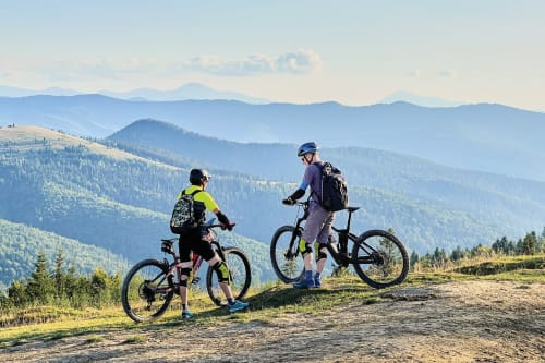 Two cyclists with helmets enjoy mountain biking above Sant'Andrea del Garigliano with scenic valley views