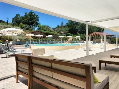 Bosco d'Olmi pool area with loungers, umbrellas, and pergola seating overlooking landscaped grounds in Sant'Andrea del