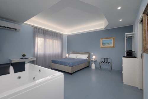 Ampia camera da letto blu con vasca idromassaggio presso BellDuomo Suite a Messina, letto king e comfort moderni