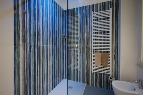 Bagno moderno con piastrelle blu righe, doccia, lavabo bianco e scaldasalviette presso BellDuomo Suite Messina