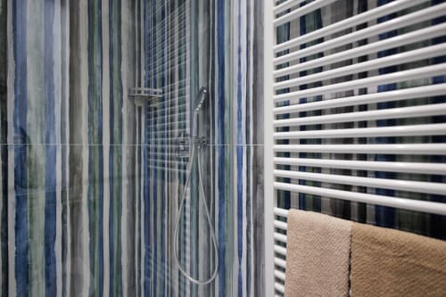 Moderno bagno con doccia, pareti a strisce blu e porta asciugamani bianca presso il BellDuomo Suite Messina