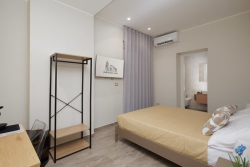 Camera moderna della BellDuomo Suite a Messina con letto matrimoniale, arredamento minimalista e vista sulla città