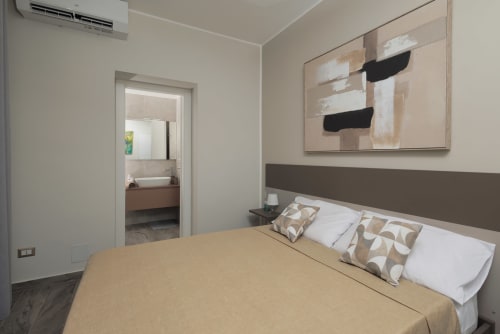 Camera moderna della BellDuomo Suite Messina con letto matrimoniale, bagno privato e opere d'arte astratta a Messina, Italia
