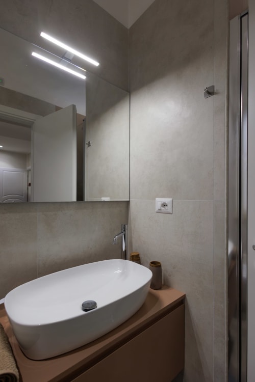 Bagno moderno della BellDuomo Suite Messina con lavabo bianco, specchio, illuminazione LED e cabina doccia