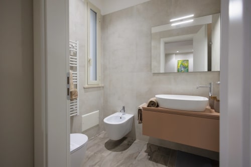 Bagno moderno della BellDuomo Suite Messina con lavabo da appoggio, bidet, scaldarughe e specchio illuminato