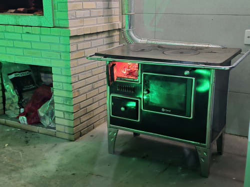 Fogão de lenha vintage verde com iluminação neon na vila Philia em Florianópolis