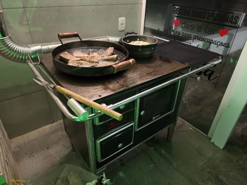 Fogão verde vintage com peixe e arroz sendo preparados na villa Philia em Florianópolis