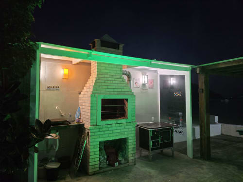 Vila do hotel Philia em Florianópolis com fachada verde vibrante, lareira de tijolos e área de pátio coberto à noite