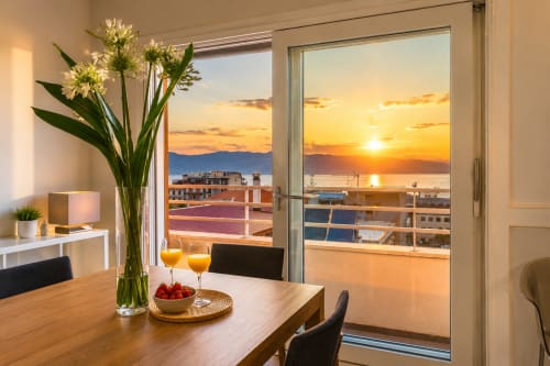 Vista sul tramonto marino dall'appartamento Pellicano Guest House a Reggio Calabria con tavolo da pranzo e fiori