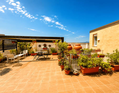Soleggiata terrazza sul tetto con piastrelle in terracotta, piante in vaso e area relax alla B&B Pellicano, Reggio Calabria