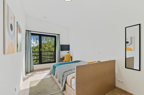 Chambre moderne à Mattbnb Metz avec vue sur la ville, lit queen-size, TV écran plat et balcon donnant sur les arbres