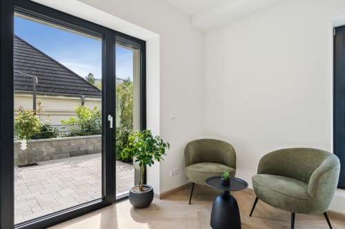 Chambre moderne Mattbnb Metz avec fauteuils verts, table d'appoint noire et vue sur la terrasse donnant sur la ville