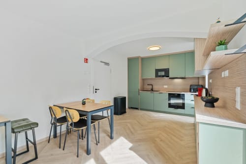 Cuisine moderne et coin repas à Ankoni Stay 3.2, Mattbnb Metz : armoires vertes, parquet, vue sur la ville