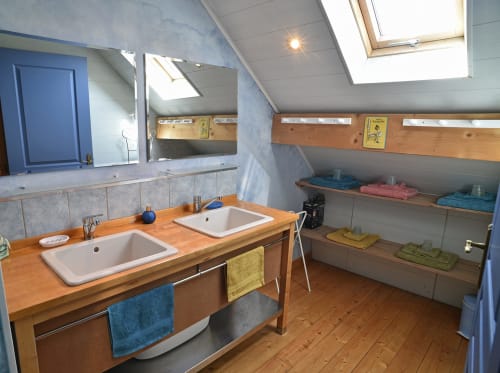 Salle de bain spacieuse avec double vasque, plan de travail en bois et rangements à la Gite Le Douglas dans le Jura