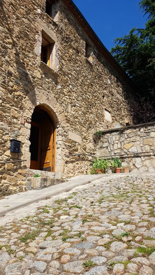 Entrada de casita de piedra con puerta arqueada amarilla en L'Orri Rectoria Nova, Campelles, con vistas a la montaña