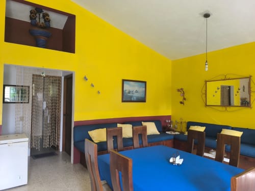 Luminosa sala de estar amarilla con mesa de comedor azul y asientos azules en la villa Casa Leticia de Monte Gordo