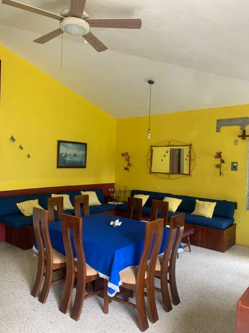 Comedor brillante en amarillo con asientos azules en la villa Casa Leticia, hotel Monte Gordo, con mesa y sillas de madera