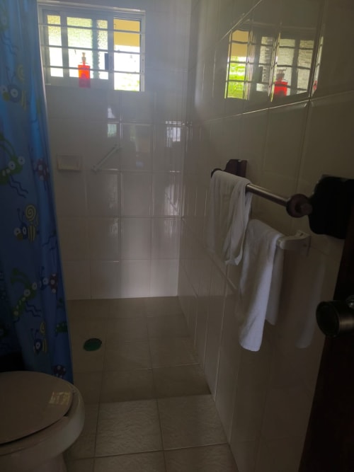 Baño moderno con cabina de ducha en villa La Morada en Monte Gordo, con toallas blancas en el toallero y vistas al jardín