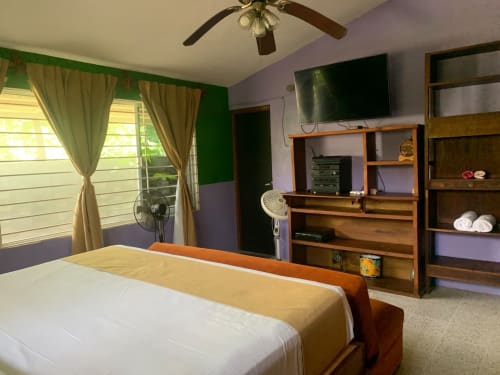 Dormitorio de la villa Casa Leticia en La Morada Monte Gordo con vistas al jardín, cama de madera, TV de pantalla plana y muebles de descanso