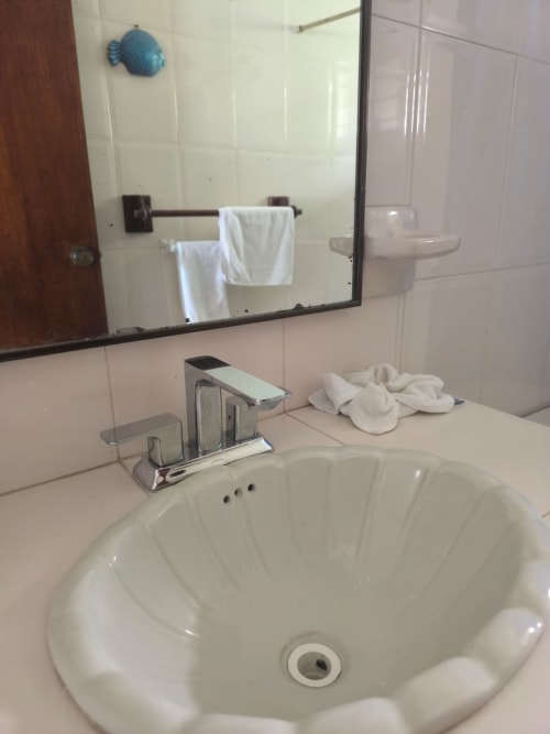 Lavabo del baño con grifo cromado, toallas blancas y espejo en la villa Casa Leticia del hotel La Morada, Monte Gordo