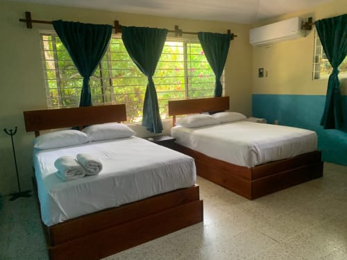 Dos camas matrimoniales con ropa de cama blanca en la villa Casa Leticia de La Morada, Monte Gordo, con vistas al jardín a través de cortinas verdes