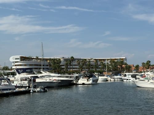 Marina luxueuse de Cap d'Agde avec yachts blancs amarrés et élégant hôtel waterfront moderne entouré de palmiers