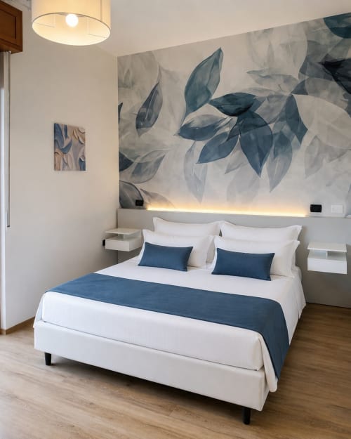 Modern deluxe hotel room at Il Mulino with blue leaf mural, white bed, dark blue accents, and ambient lighting