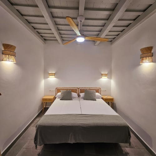 Dormitorio moderno en Casa De La Cruz Vejer con cama de ratán, vigas de madera, apliques tejidos y ventilador de techo