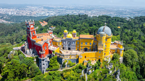 Palácio da Pena colorido em Sintra, Portugal, cercado por florestas verdes e vistas da cidade ao longe