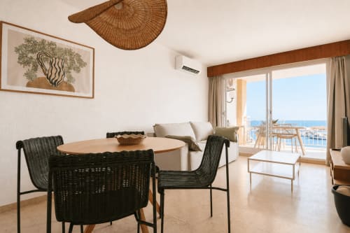 Moderno apartamento en Calpe con balcón con vistas al mar, comedor con sillas de mimbre negro, paisaje costero