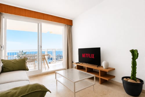 Moderno salón con vistas al mar en Calpe, Netflix en TV, muebles de madera y planta de cactus en maceta