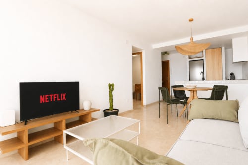 Moderno salón de apartamento en Calpe con Netflix en TV, muebles de madera y vistas al mar en Riurau Home