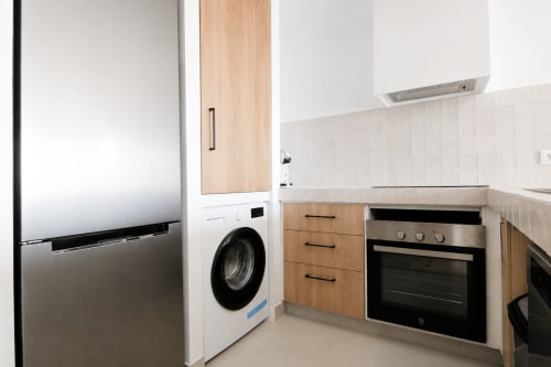 Cocina moderna en apartamento Riurau Home, Calpe, con electrodomésticos de acero inoxidable, muebles de madera y lavadora integrada