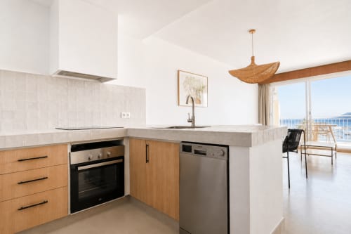Cocina moderna con armarios de madera, vistas al mar desde el balcón del apartamento Riurau Home en Calpe