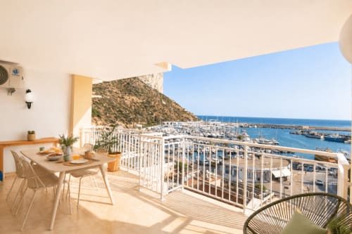 Balcón con mesa de comedor con vistas a la marina de Calpe y el mar Mediterráneo en el apartamento Riurau Home