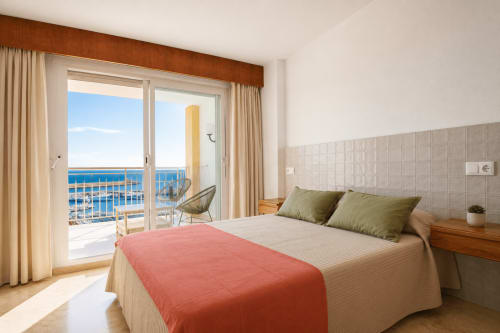 Luminoso dormitorio con balcón vistas al mar en Riurau Home, Calpe - cama moderna con manta roja y almohadas verdes